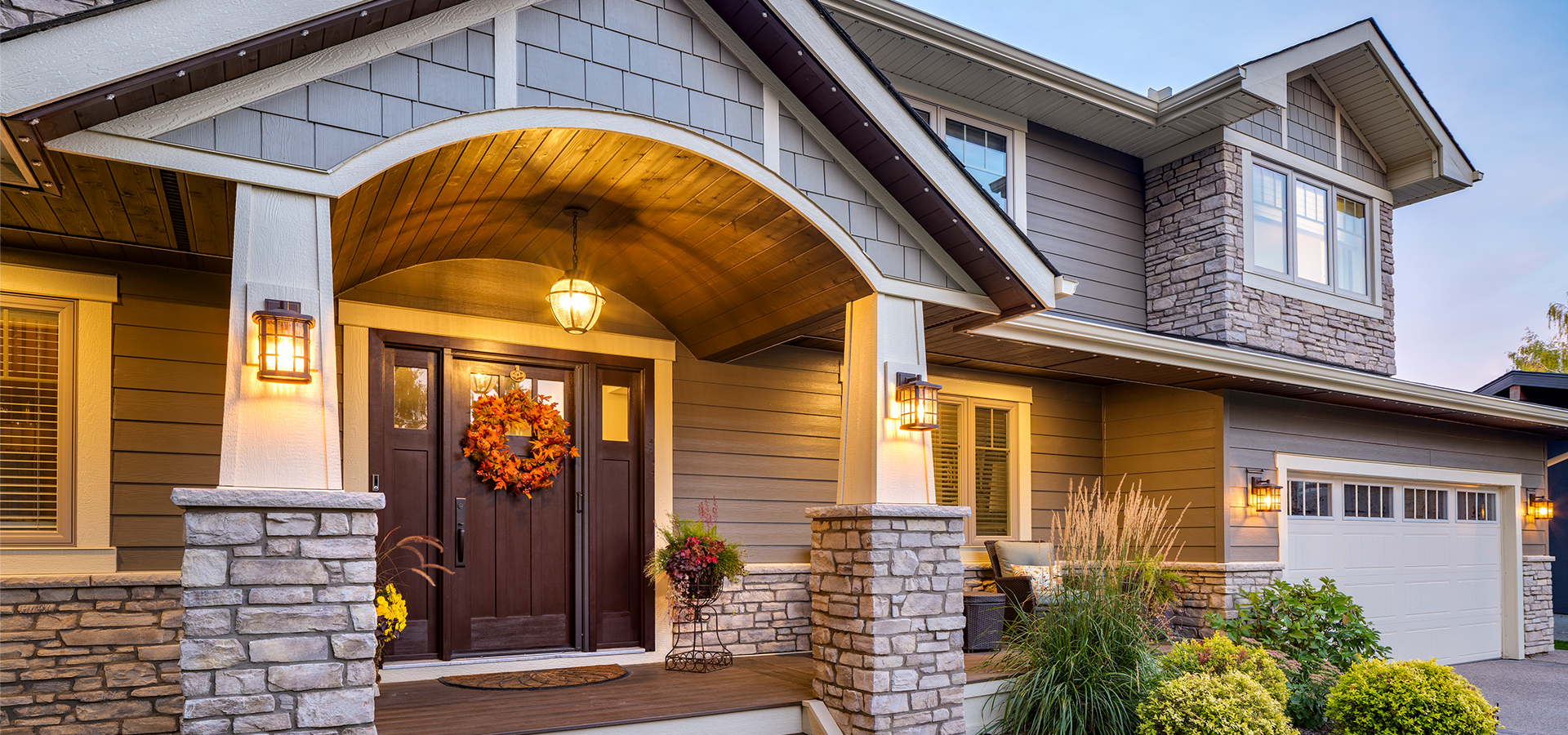 A newly renovated home exterior with rock accents and beautiful lighting.