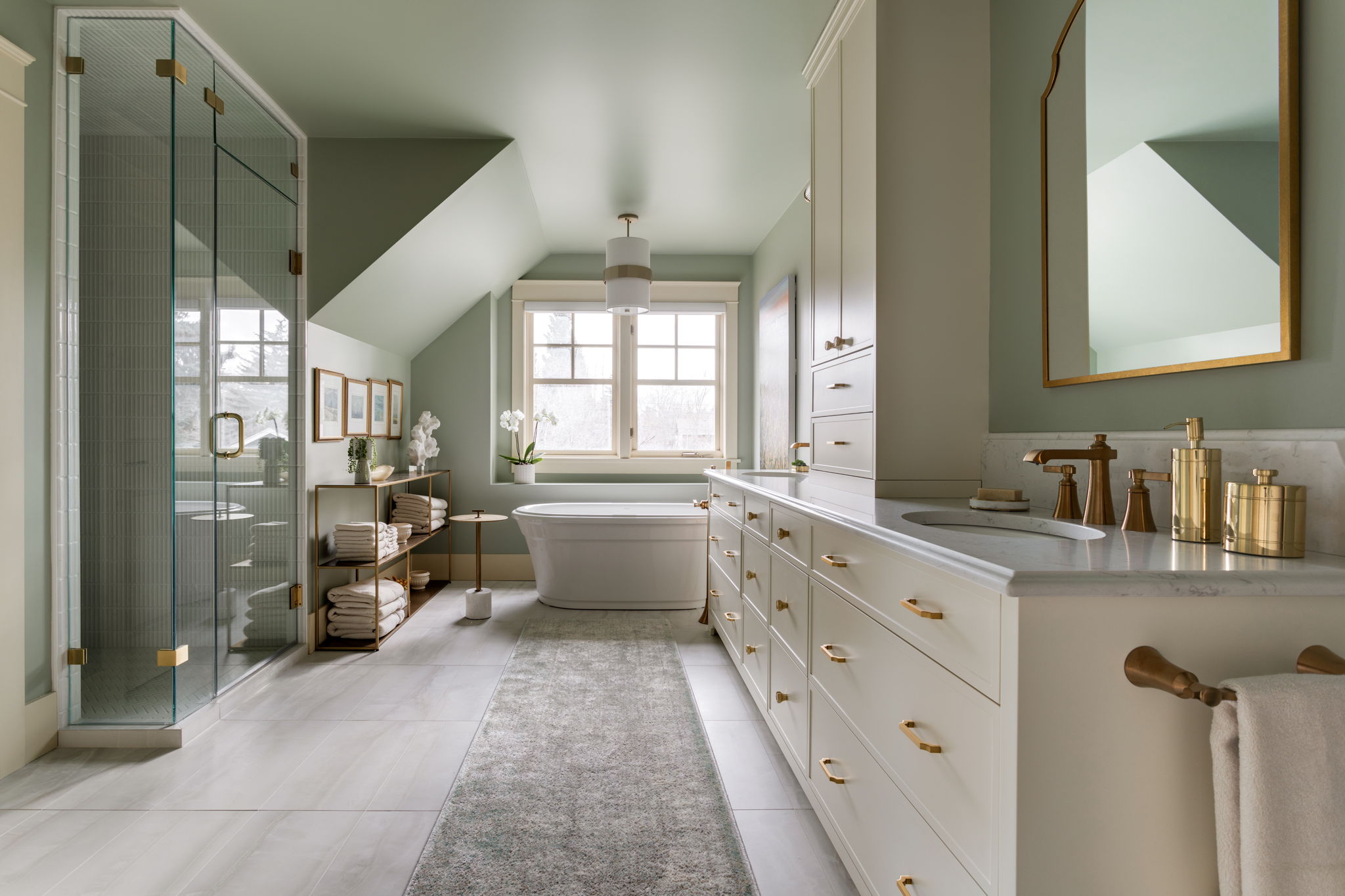 Luxurious bathroom with cream cabinets, gold fixtures, a freestanding tub and double vanity.