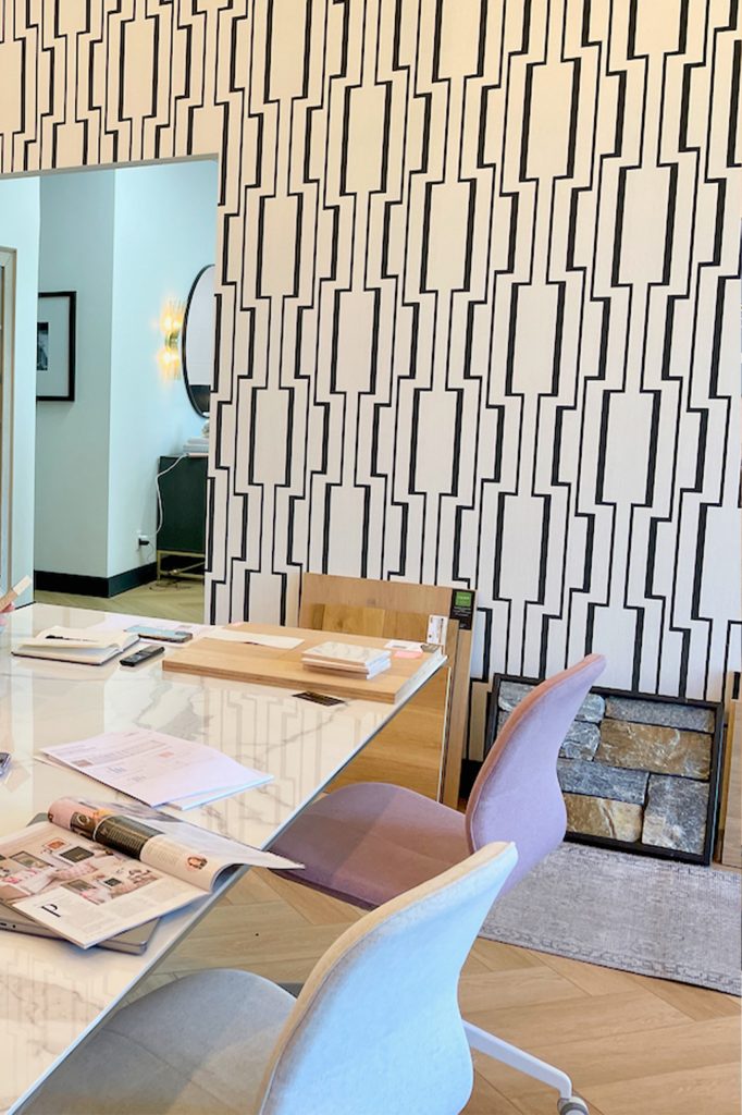 The boardroom in a Calgary interior design studio with modern patterned wall paper and design samples on the table and floor.